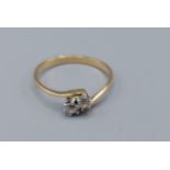 An 18ct gold two stone diamond ring, the two diamonds in a cross over setting, 1.6gms, ring size K