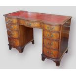 A mahogany serpentine fronted twin pedestal desk, the tooled leather inset top above nine drawers