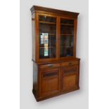 An Edwardian walnut bookcase by Maple & Co, the moulded cornice above two glazed doors enclosing