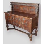 An Edwardian carved oak side cabinet, the carved panel back with end pillars above a moulded top