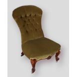 A Victorian low seat chair, the shaped button back above a stuff over seat raised upon shaped carved