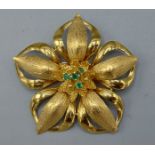 An 18ct yellow gold and emerald brooch in the form of a flower head set four central emeralds,