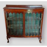 A mahogany bow fronted display cabinet, the moulded top above to bar glazed doors enclosing