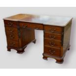 An Edwardian mahogany twin pedestal desk, the inverted moulded top above nine drawers with brass