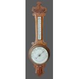 An Edwardian carved oak Aneroid barometer thermometer