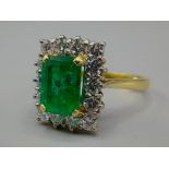 A yellow metal Diamond and Emerald cluster ring set central rectangular Emerald surrounded by