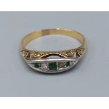 An 18ct gold Emerald and Diamond ring, set with three Emeralds and two Diamonds within a pierced