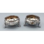 A pair of Victorian silver salts of circular embossed form raised upon three low feet, Birmingham