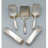 A Birmingham silver backed five piece dressing table set comprising four brushes and a hand mirror