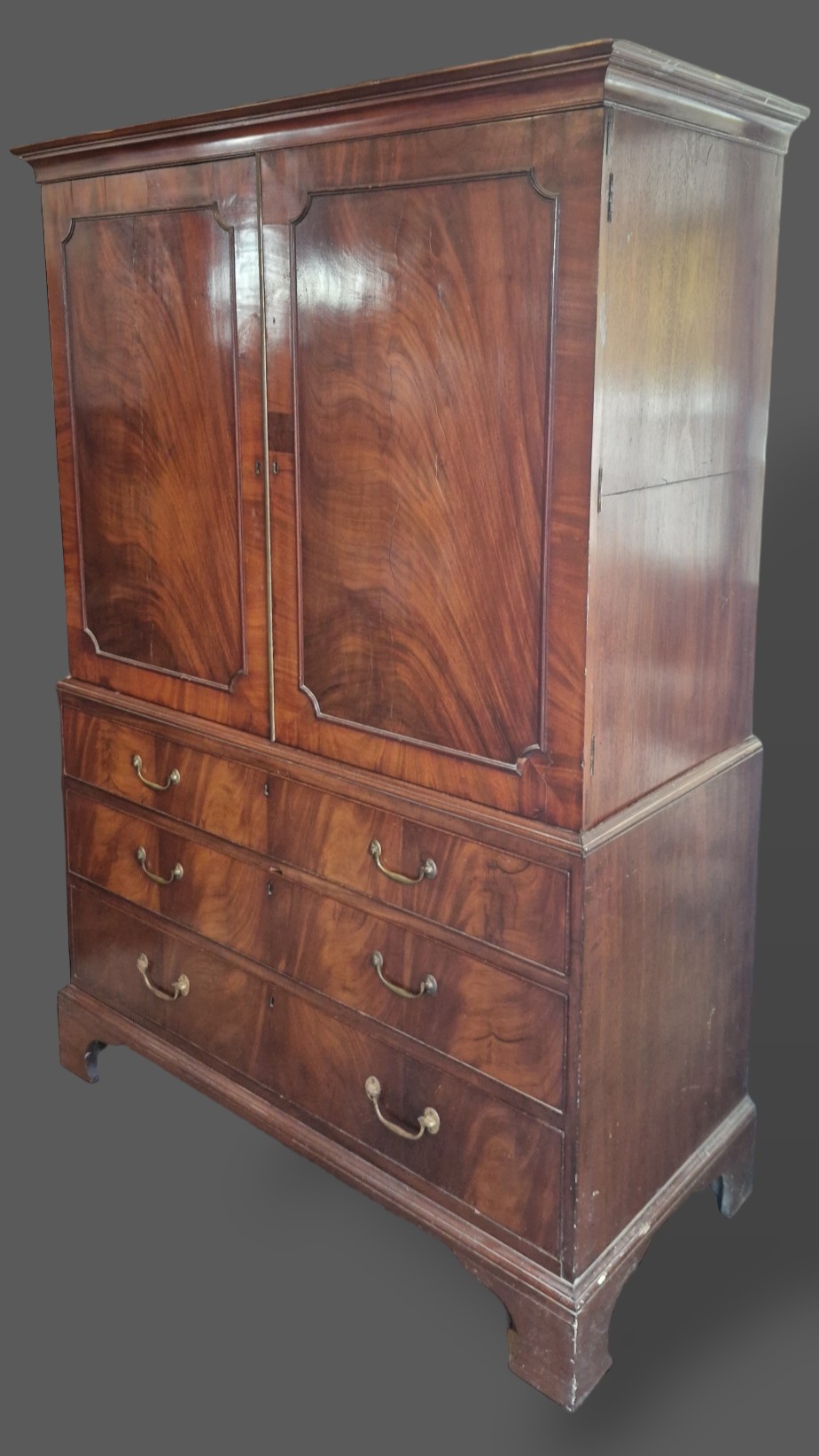 A 19th Century mahogany press cupboard, the moulded cornice above two panel doors enclosing trays