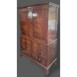 A 19th Century mahogany press cupboard, the moulded cornice above two panel doors enclosing trays