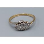 An 18ct gold and diamond ring set with three diamonds in a crossover setting, ring size L, 2.1gms