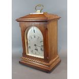 An early 20th Century German walnut cased mantle clock with brass carrying handle, 46cms tall