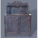 An oak side cabinet with a triple carved back with turned uprights above two carved doors raised