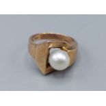 A 9ct gold and pearl ring set with single pearl within an abstract setting, ring size K, 4.2gms