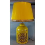 A Toleware table lamp decorated with an Armorial crest upon a mustard ground with Toleware shade,