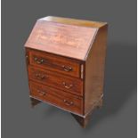 An Edwardian mahogany marquetry inlaid bureau with hinged writing surface above three drawers raised