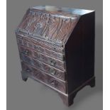 A George III carved oak bureau, the fall front enclosing a fitted interior above four drawers raised