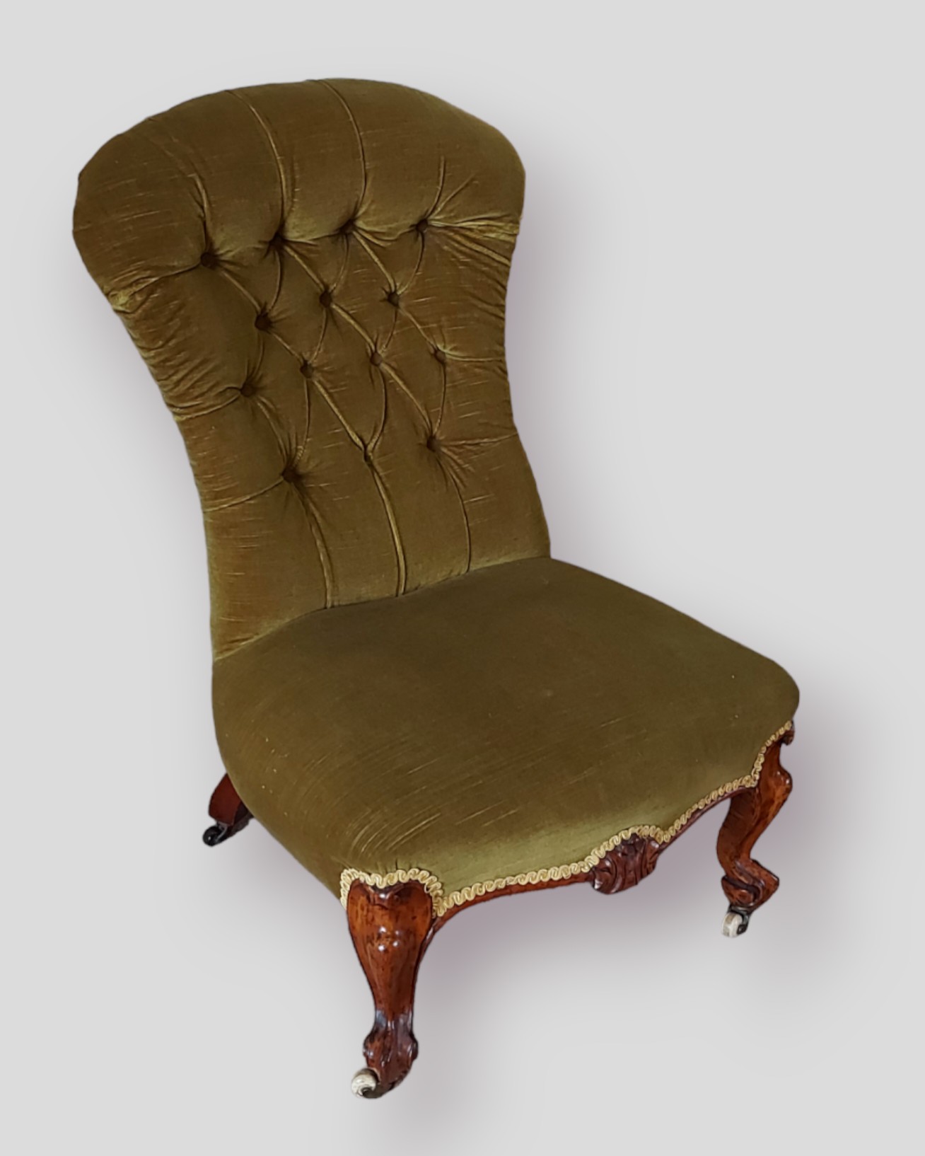 A Victorian low seat chair, the shaped button back above a stuff over seat raised upon shaped carved