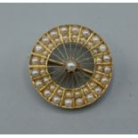 A yellow metal brooch in the form of a wheel set with pearls, 2.3cms diameter, 7.1gms