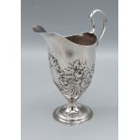 A George III silver cream jug with embossed decoration and shaped handle, London 1787, 13cms tall