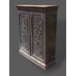 A 19th Century carved oak side cabinet with two doors above a plinth, 100cms wide, 31cms deep and