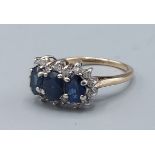 A 9ct gold Sapphire and Diamond ring set with three Sapphires surrounded by Diamonds5.9gms, ring