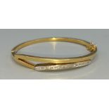 An 18ct gold bangle inset with thirteen diamonds, 6cms by 5cms, 13.4gms