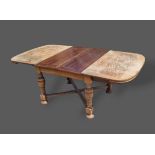 A 1930's oak Majik drawer leaf extending dining table raised upon turned legs with stretchers,