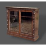 A Victorian carved oak bookcase with two glazed doors above a plinth, 123cms wide, 33cms deep and