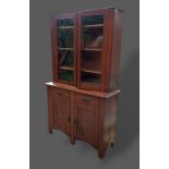 An Art Nouveau mahogany bookcase with two glazed doors above two drawers and two cupboard doors,