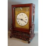 A 19th Century Chinese hardwood cased bracket clock, the pieced carved case with engraved brass