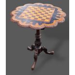 A Victorian walnut and ebonised games table, the chess board top above a carved column raised upon