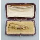 A 9ct gold brooch set with a central ruby flanked by diamonds within original box, 3.9gms