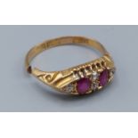 An 18ct gold ring set with two rubies and four diamonds, (band cut)