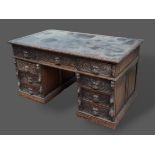 A Victorian carved oak twin pedestal desk with nine drawers with mask head handles raised upon