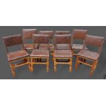 A set of eight oak dining chairs each with a leather back and seat raised upon turned legs and