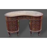 An Edwardian mahogany kidney shaped writing desk by Maple and Co. The tooled inset top above nine