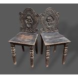 A pair of Victorian carved oak hall chairs, each with a shaped pierced back above a panel seat and