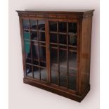 An oak bookcase, the moulded top above two glazed doors, raised upon a plinth, 108cms wide, 38cms