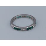 A white gold Emerald and diamond set full eternity ring, 2.8gms, ring size M