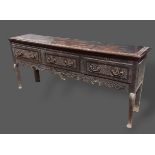 A George III oak dresser base, the carved and moulded top above three drawers with brass handles