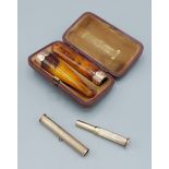 A 9ct gold cigar piercer together with a pair of amber and 9ct gold cheroot holders in fitted box