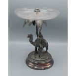 A Sheffield plated table centre in the form of a camel and rider by a palm tree with glass bowl,