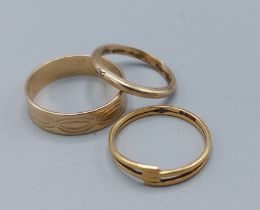 An 18ct gold band ring, 1.3gms, together with a 9ct gold wedding band, 1.8gms and an unmarked band