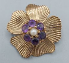 A 9ct gold brooch of flower head form set with a central Amethyst surrounded by pearls, 7gms