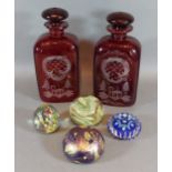 A pair of red flash decanters with stoppers together with four glass paperweights