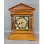 An early 20th Century oak mantle clock, the brass dial with Roman numerals and three train