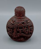 A Chinese carved cinnabar scent bottle, decorated with figures within a landscape, 9cms tall