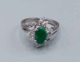 An 18ct white gold Emerald and diamond ring set with a cabochon emerald surrounded by Marquise cut